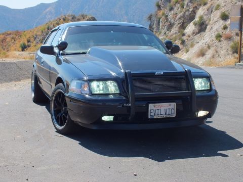 2003 Ford Crown Victoria - Front of a blacked-out Crown Vic showing grille guard, fog lights and black wheels.
