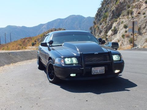 2003 Ford Crown Victoria - Angled front view of a Crown Vic with push bar against dry hillsides and clear sky.