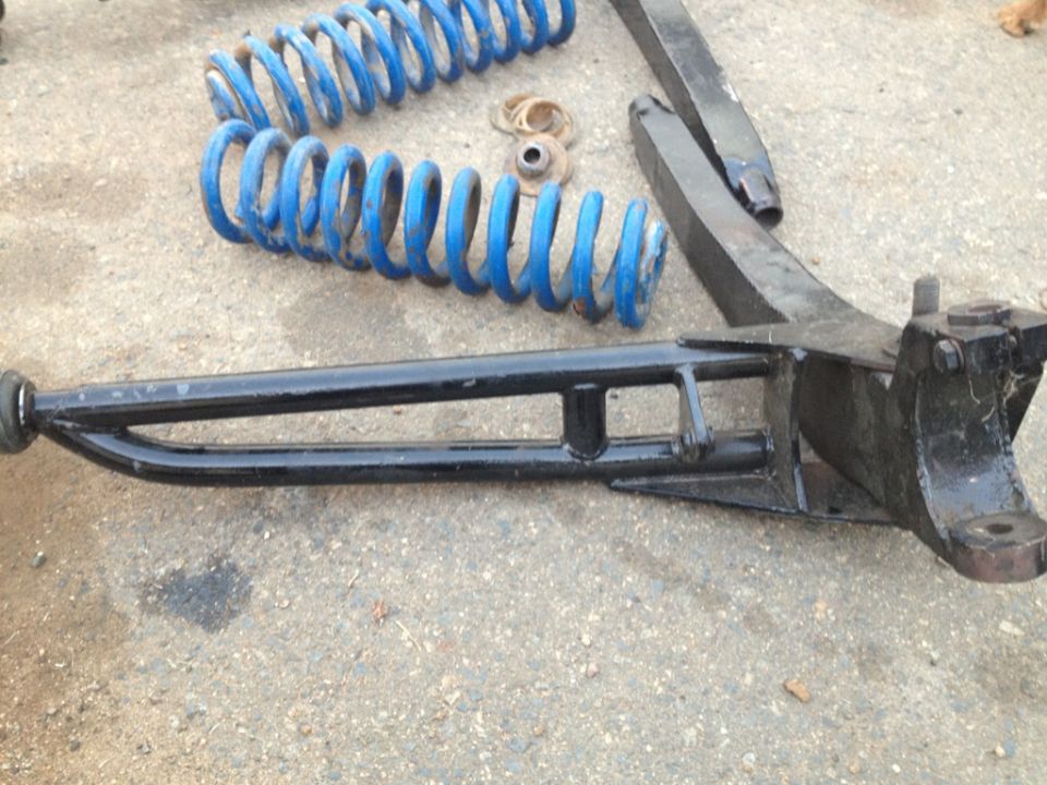 Blue coil springs and black suspension components laid out on the ground