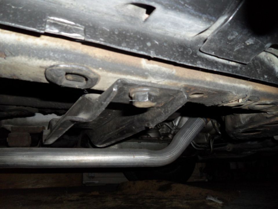 Undercarriage view of a vehicle's exhaust pipe and frame support