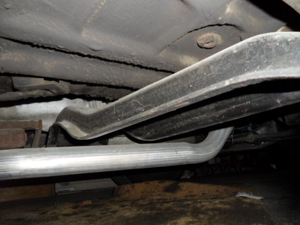 Underside view of a vehicle showing the exhaust pipe and frame components
