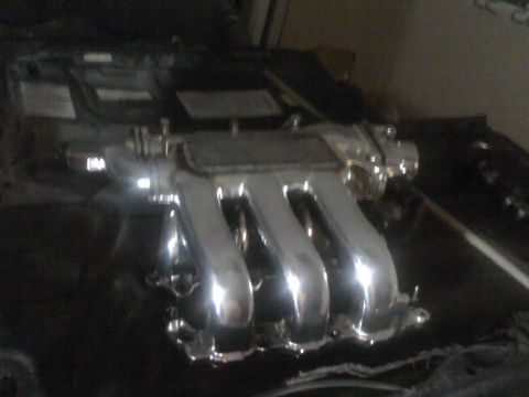 1995 Ford Probe - A shiny chrome intake manifold is shown, likely a replacement part for a vehicle.