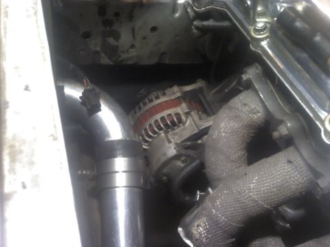 1995 Ford Probe - Close-up view of engine components including the alternator and exhaust manifold with heat wrap.