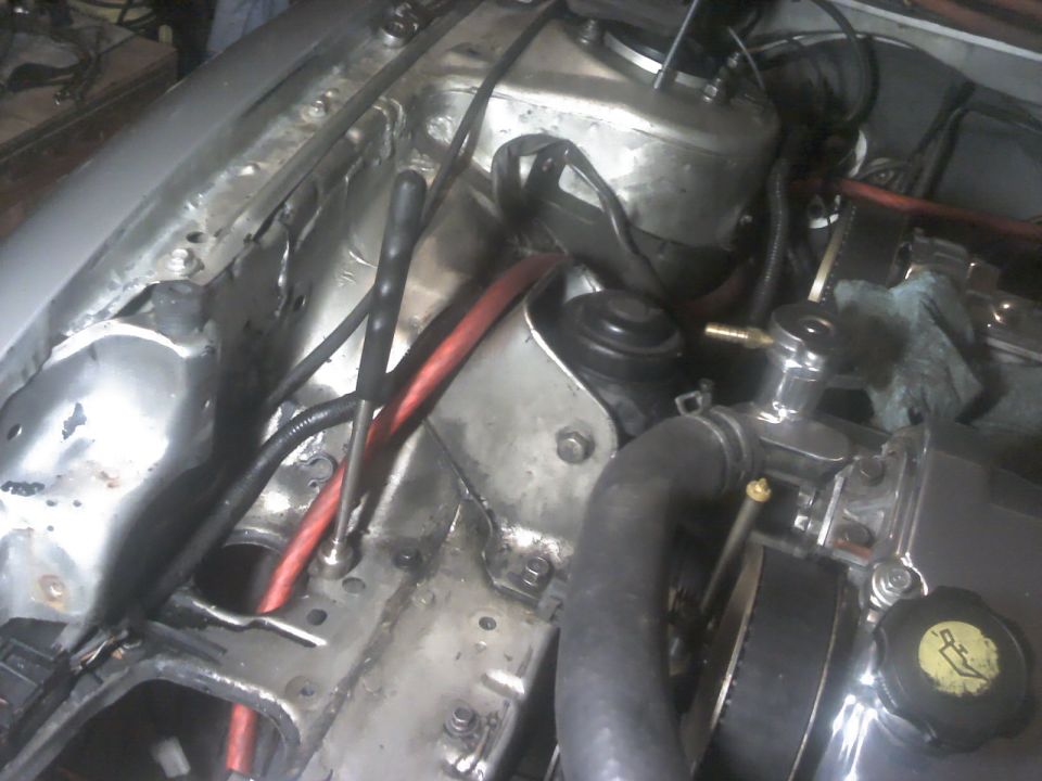 Engine bay with red hoses, metal components, and black wiring