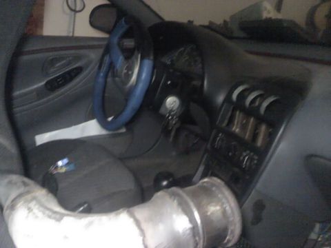 1995 Ford Probe - Interior view of a car with a modified steering wheel and a large exhaust pipe visible.