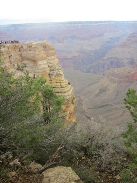1991 Ford LTD Crown Victoria - A wide view of the Grand Canyon shows layered rock formations and a distant haze, with a group of people on a cliff overlook.