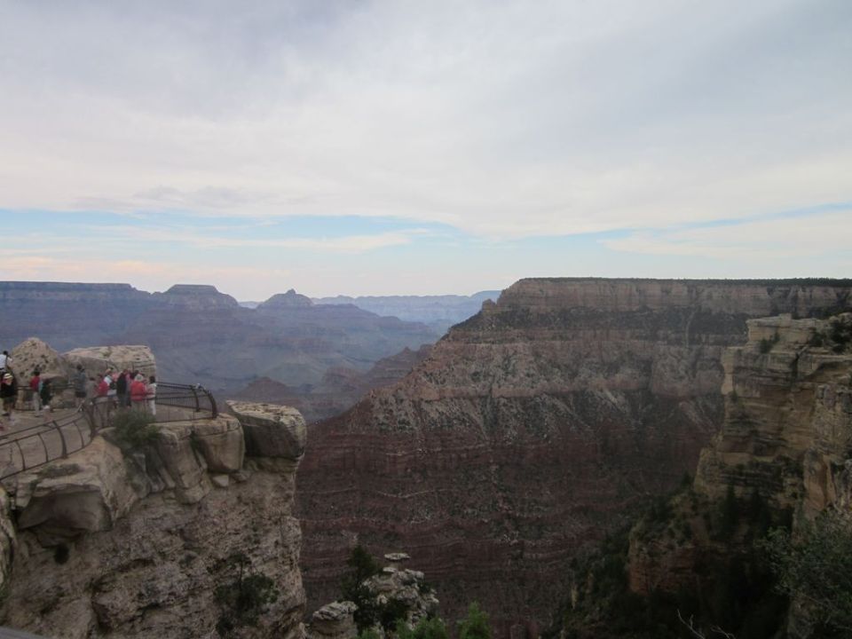 Grand Canyon overlook with tourists and a Supermotors watermark