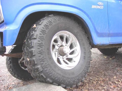 1980 Ford Bronco - Close-up of a blue 1980 Ford Bronco's front wheel and fender, with the Bronco badge visible.