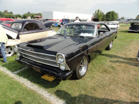 1964 Ford Fairlane - A black 1966 Ford Fairlane GT is displayed at a car show, a prominent hood scoop and custom chrome wheels.