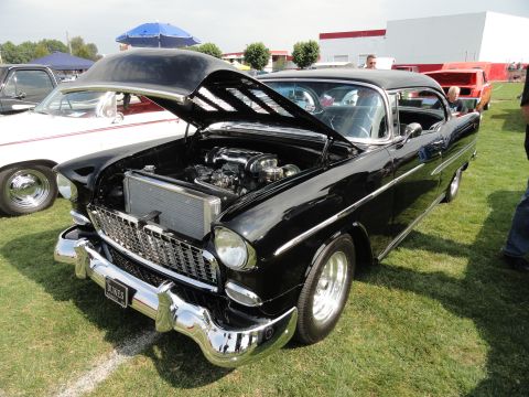 1964 Ford Fairlane - A black 1955 Chevrolet Bel Air is displayed with its hood open at a car show.