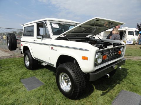 1964 Ford Fairlane - First-generation Ford Bronco on display at a car show, with its hood raised to reveal the engine.