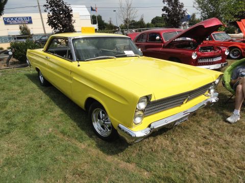 1964 Ford Fairlane - A yellow 1965 Mercury Comet is displayed at an outdoor car show.