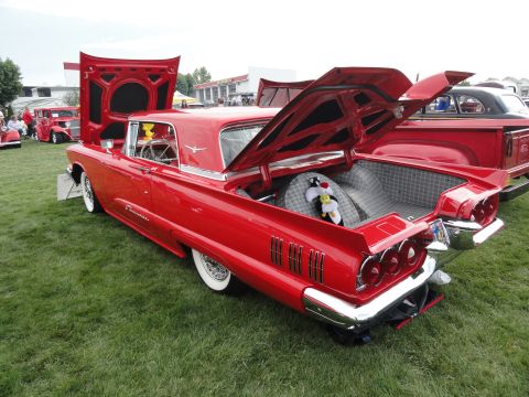 1964 Ford Fairlane - A classic red 1958 Ford Thunderbird is displayed with its hood and trunk open at an outdoor car show.