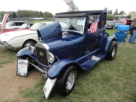 1964 Ford Fairlane - A blue Ford Model T coupe is displayed at a car show with other vehicles in the background.
