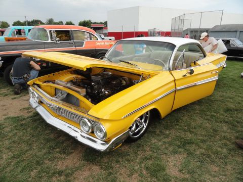 1964 Ford Fairlane - A bright yellow 1961 Chevrolet Impala coupe is displayed with its hood open at a car show.