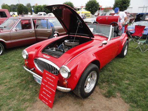 1964 Ford Fairlane - A red 1963 Austin Healey 3000 Mark III is displayed with its hood open at an outdoor car show.