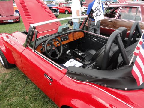 1964 Ford Fairlane - Interior view of a red convertible at a car show, with other vehicles visible in the background.