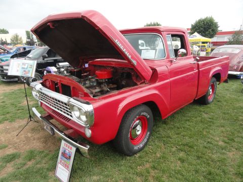 1964 Ford Fairlane - A red 1958 Ford F-100 pickup truck is displayed with its hood open at a car show.