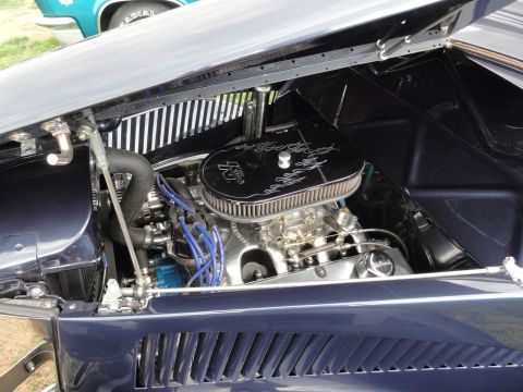 1964 Ford Fairlane - A dark blue car's engine bay is visible, a chrome air cleaner and blue spark plug wires.