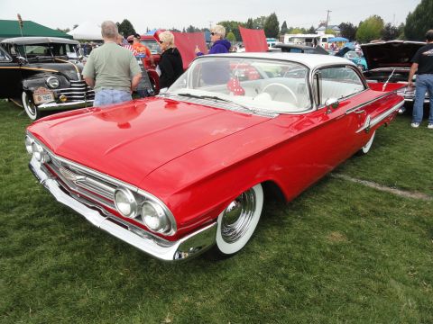 1964 Ford Fairlane - A red and white 1960 Chevrolet Impala is parked on grass at a car show with other vehicles around.