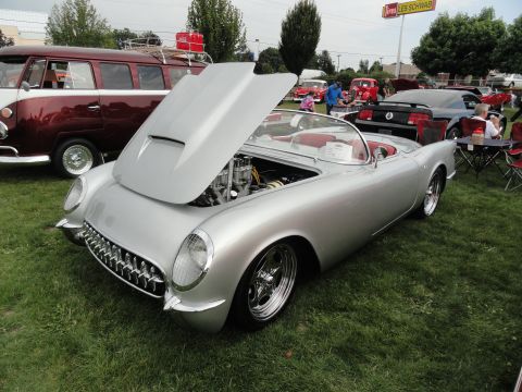 1964 Ford Fairlane - A silver 1955 Chevrolet Corvette convertible is displayed with its hood open at a car show, revealing the engine and red interior.