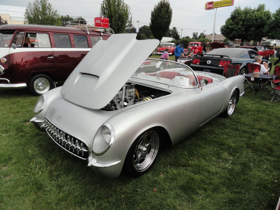 Silver 1955 Chevrolet Corvette convertible with hood open, red interior, chrome grille