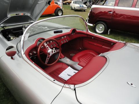1964 Ford Fairlane - The interior of a classic silver convertible with red upholstery is shown, with other vehicles in the background.
