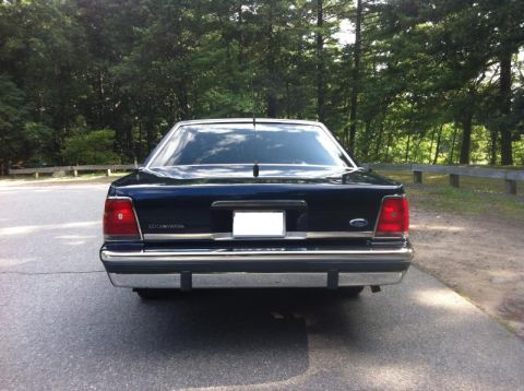 1991 Ford LTD Crown Victoria - Rear view of a dark blue 1991 Ford Crown Victoria LTD parked on an asphalt surface with trees in the background.