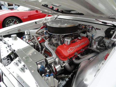 1964 Ford Fairlane - Engine bay of a white car with a red Chevrolet engine and chrome accents, with a red car visible in the background.