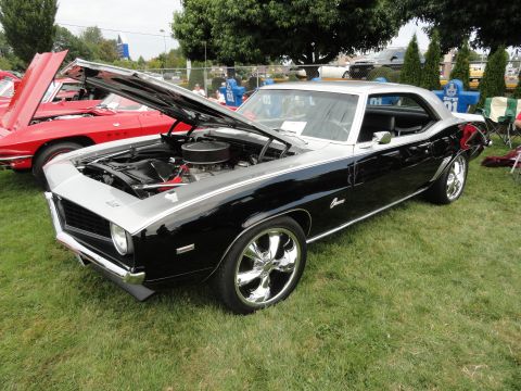 1964 Ford Fairlane - A black and silver 1969 Chevrolet Camaro is displayed with its hood open at a car show.