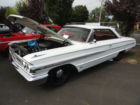 1964 Ford Fairlane - White 1964 Ford Fairlane displayed at a car show with its hood up.