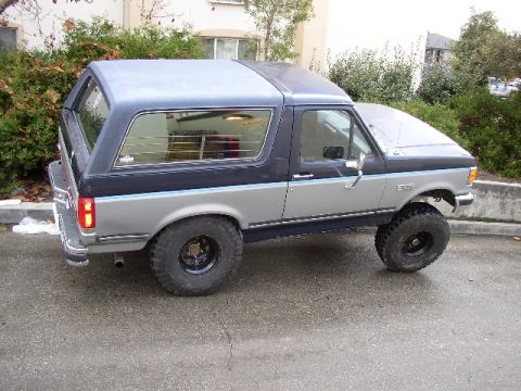 1989 Ford Bronco - This Ford Bronco features a two-tone paint scheme and is equipped with large off-road tires.