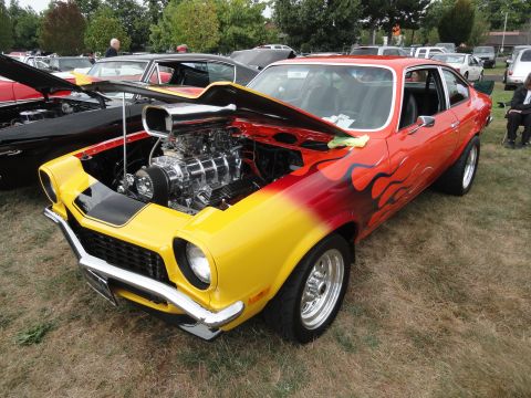1964 Ford Fairlane - A heavily modified car with a prominent supercharger and flame paint job is displayed at a car show.