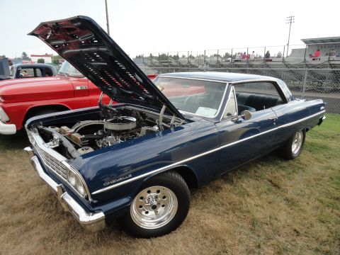 1964 Ford Fairlane - A dark blue 1964 Chevrolet Chevelle is displayed with its hood open at a car show, revealing the engine and polished wheels.