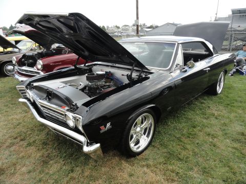 1964 Ford Fairlane - A black 1967 Chevrolet Chevelle SS is displayed with its hood open, revealing the engine bay.