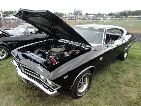 1964 Ford Fairlane - Black 1969 Chevrolet Chevelle SS at a car show, engine exposed.