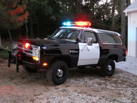 1987 Dodge 1500 - This modified SUV is equipped with a light bar and push bumper, resembling a police vehicle.