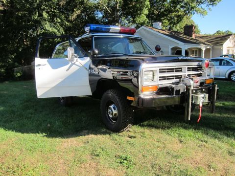 1987 Dodge 1500 - Front view of a 1987 Dodge 1500 police truck, showing the open driver's door and emergency light bar.