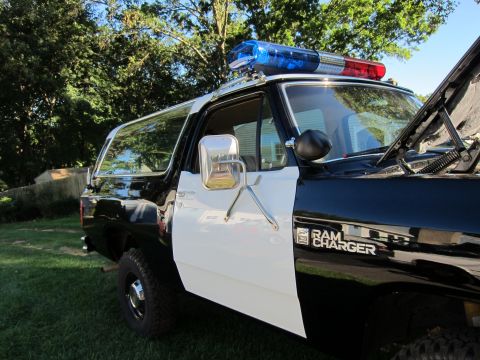 1987 Dodge 1500 - This police SUV, likely from the 1980s, has its hood up and is parked on grass.