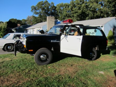 1987 Dodge 1500 - This 1987 Dodge 1500 police SUV features a distinctive two-tone black and white paint scheme and a rooftop light bar.