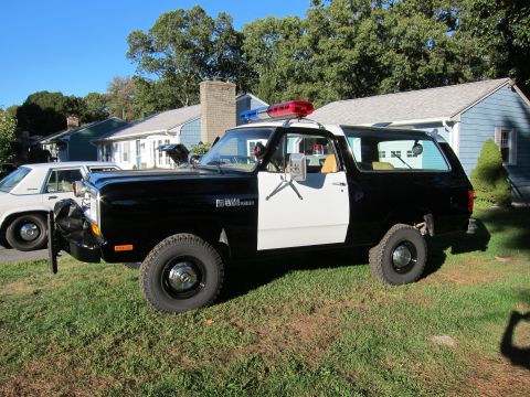 1987 Dodge 1500 - This 1987 Dodge 1500 police SUV is parked on a grassy lawn next to a residential house.