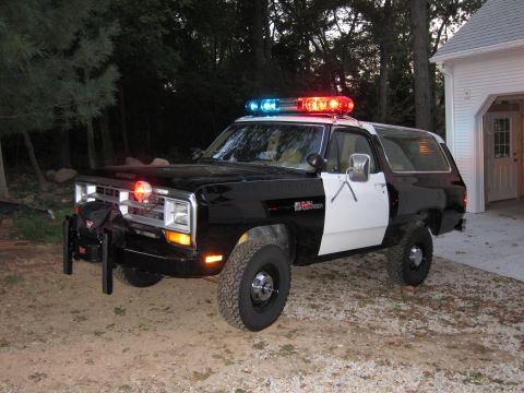 1987 Dodge 1500 - This SUV, modified to resemble a police vehicle, has a distinctive boxy body style common in the 1980s.
