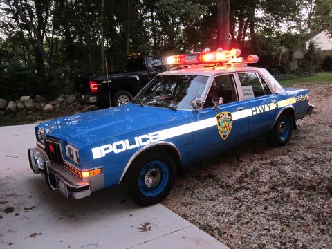 1987 Dodge 1500 - This police car, likely from the 1980s, is parked next to a modern pickup truck.