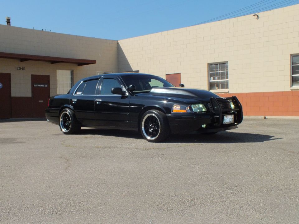 Black Ford Crown Victoria front profile with push bar in industrial parking lot