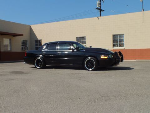 2003 Ford Crown Victoria - Side view of a lowered Crown Vic with amber marker light glowing in an industrial lot.