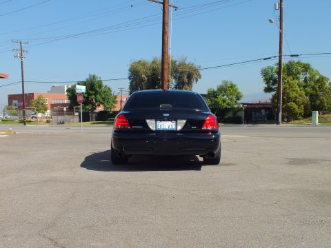 2003 Ford Crown Victoria - Straight-on rear view of a lowered black Crown Victoria with EVIL VIC plate in a wide open parking lot.