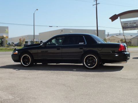 2003 Ford Crown Victoria - Full side profile of a slammed black Crown Victoria parked outside a Sonic Plating sign.