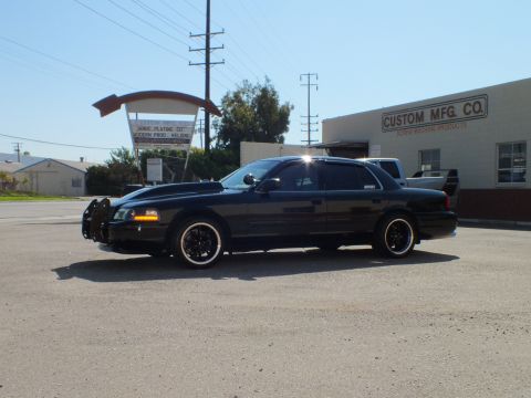 2003 Ford Crown Victoria - Black Crown Victoria with push bar shown from the front side in an industrial parking lot.