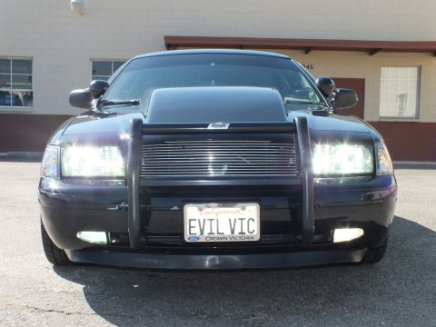 2003 Ford Crown Victoria - Close front view showing the billet grille, lit projector headlights and EVIL VIC Crown Victoria plate.