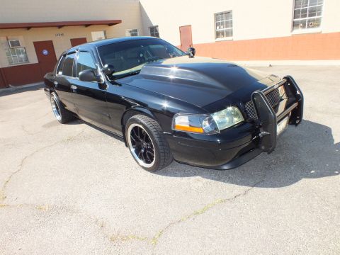 2003 Ford Crown Victoria - Passenger-front angle of a lowered black Crown Victoria fitted with a grille guard in a building lot.